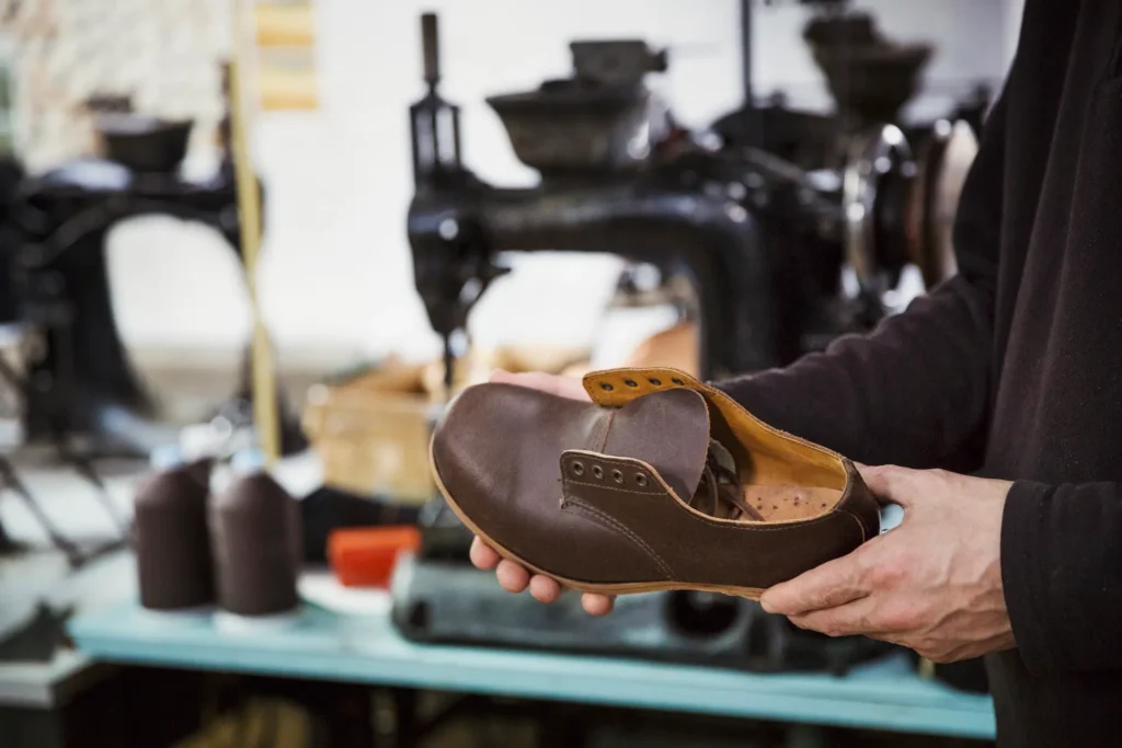 man standing in a shoemaker s workshop holding br 2025 04 05 06 58 04 utc